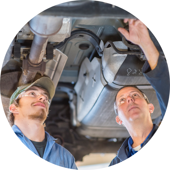 Two men working on the underside of a car.