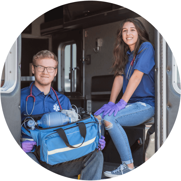Two students sitting in the back of an ambulance during a medical training exercise.